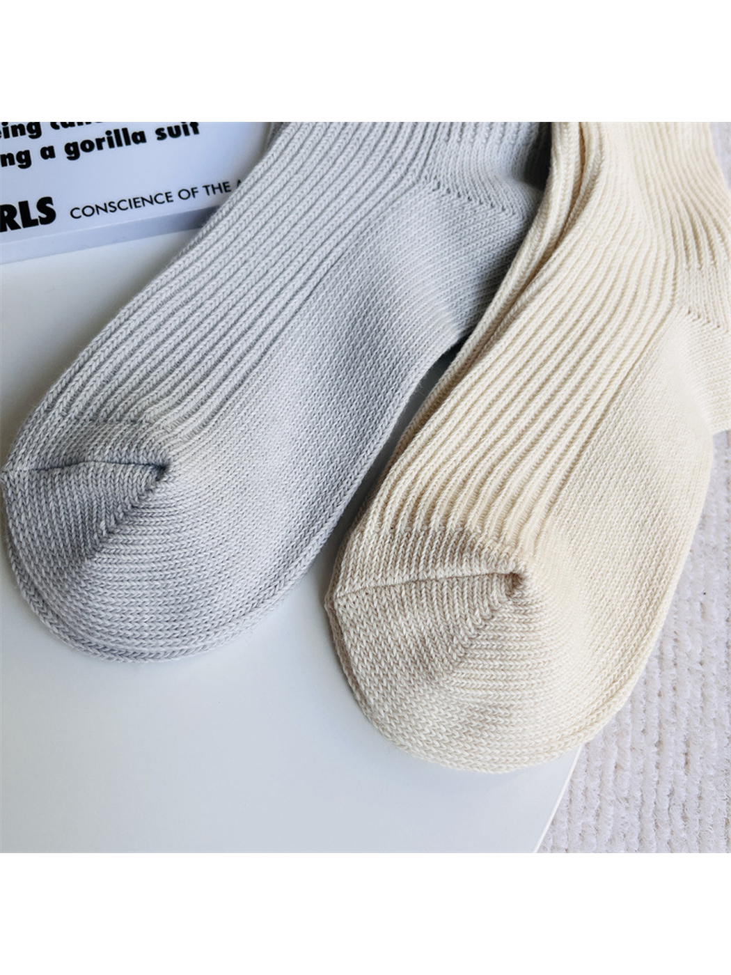 Close-up of light gray and ivory socks with rounded knit toes