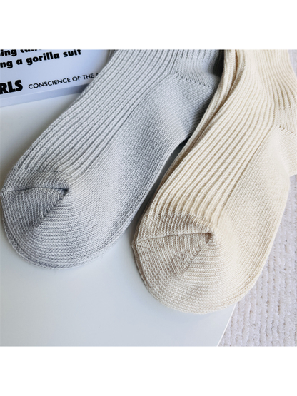 Close-up of light gray and ivory socks with rounded knit toes