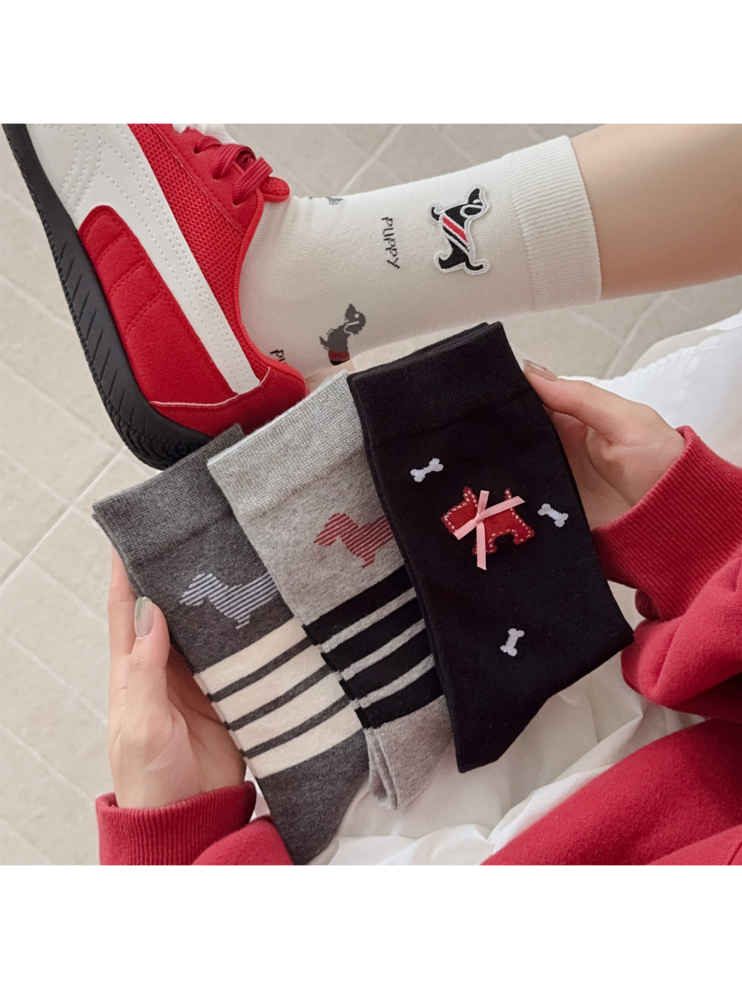 Four dog-motif crew sock styles displayed with an ivory pair worn with red sneakers