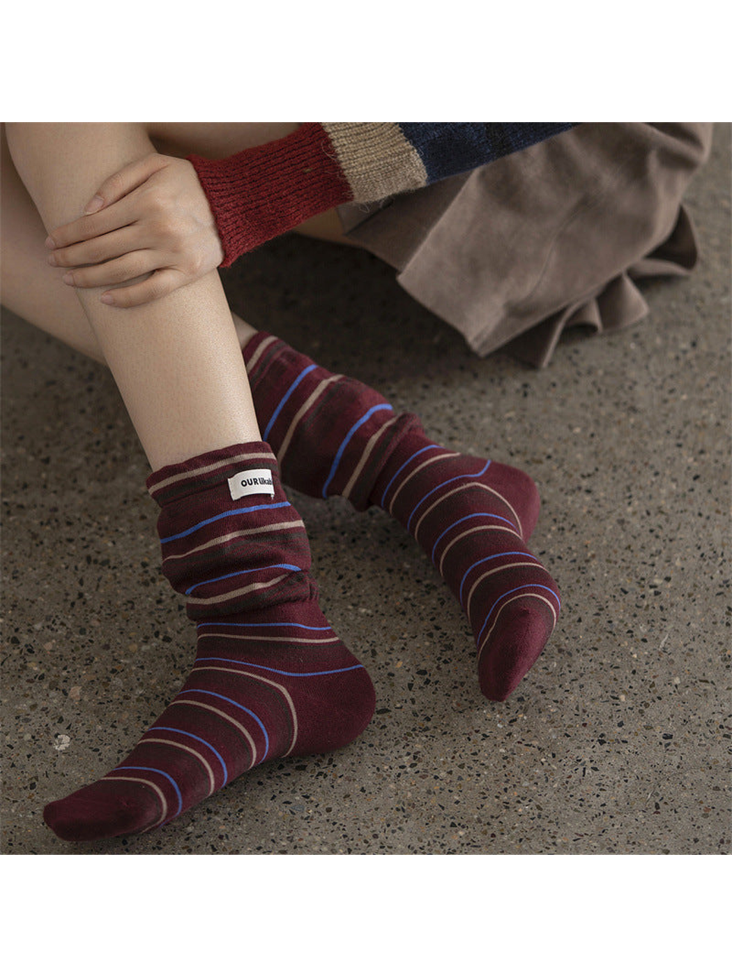Burgundy striped socks worn scrunched at the ankles