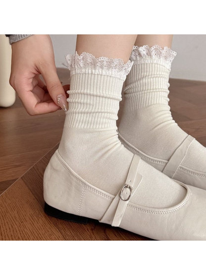Ivory lace-trim crew socks worn scrunched above white Mary Jane shoes