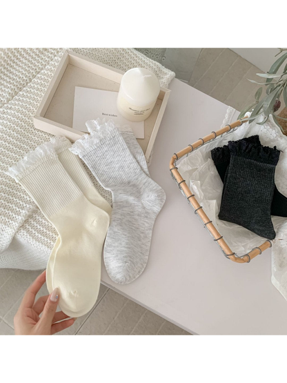 Ivory, light gray, dark gray and black lace-trim crew socks arranged together