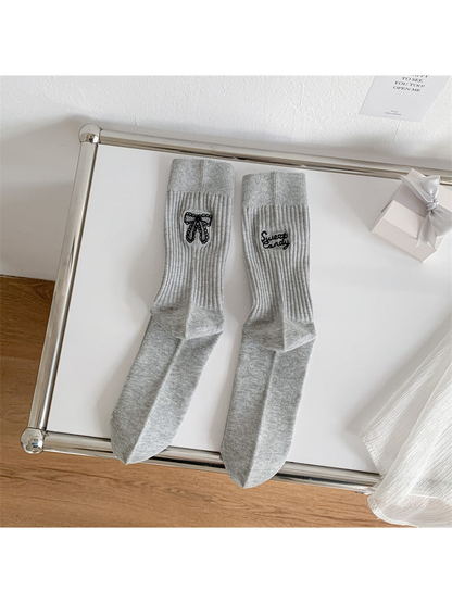 Light gray ribbed crew socks with black bow and script embroidery