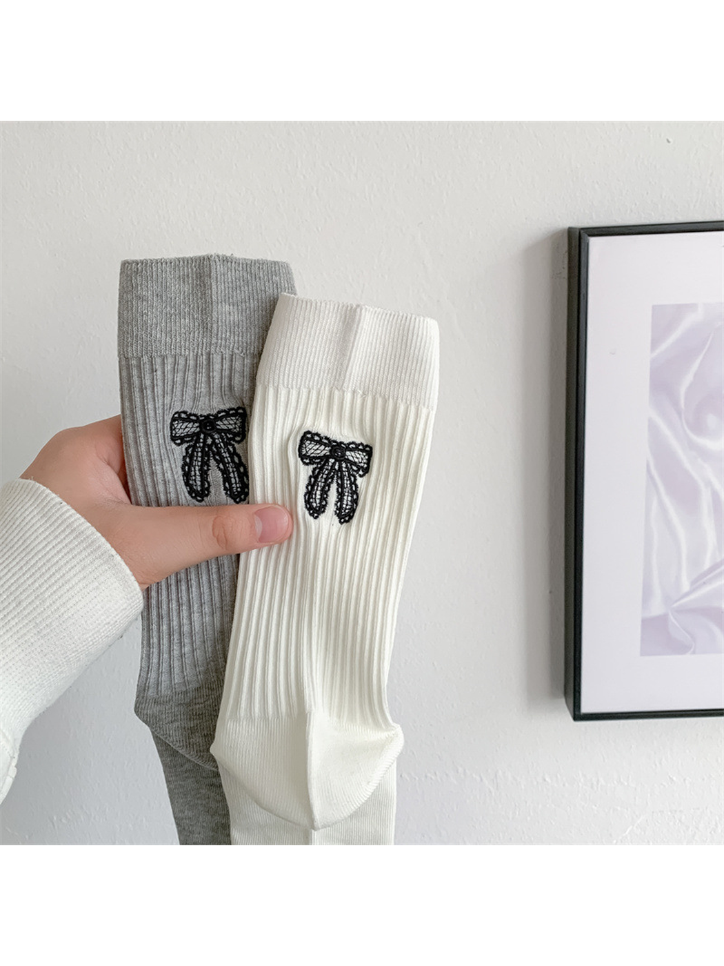 Close-up of black bow embroidery on ivory and light gray ribbed socks
