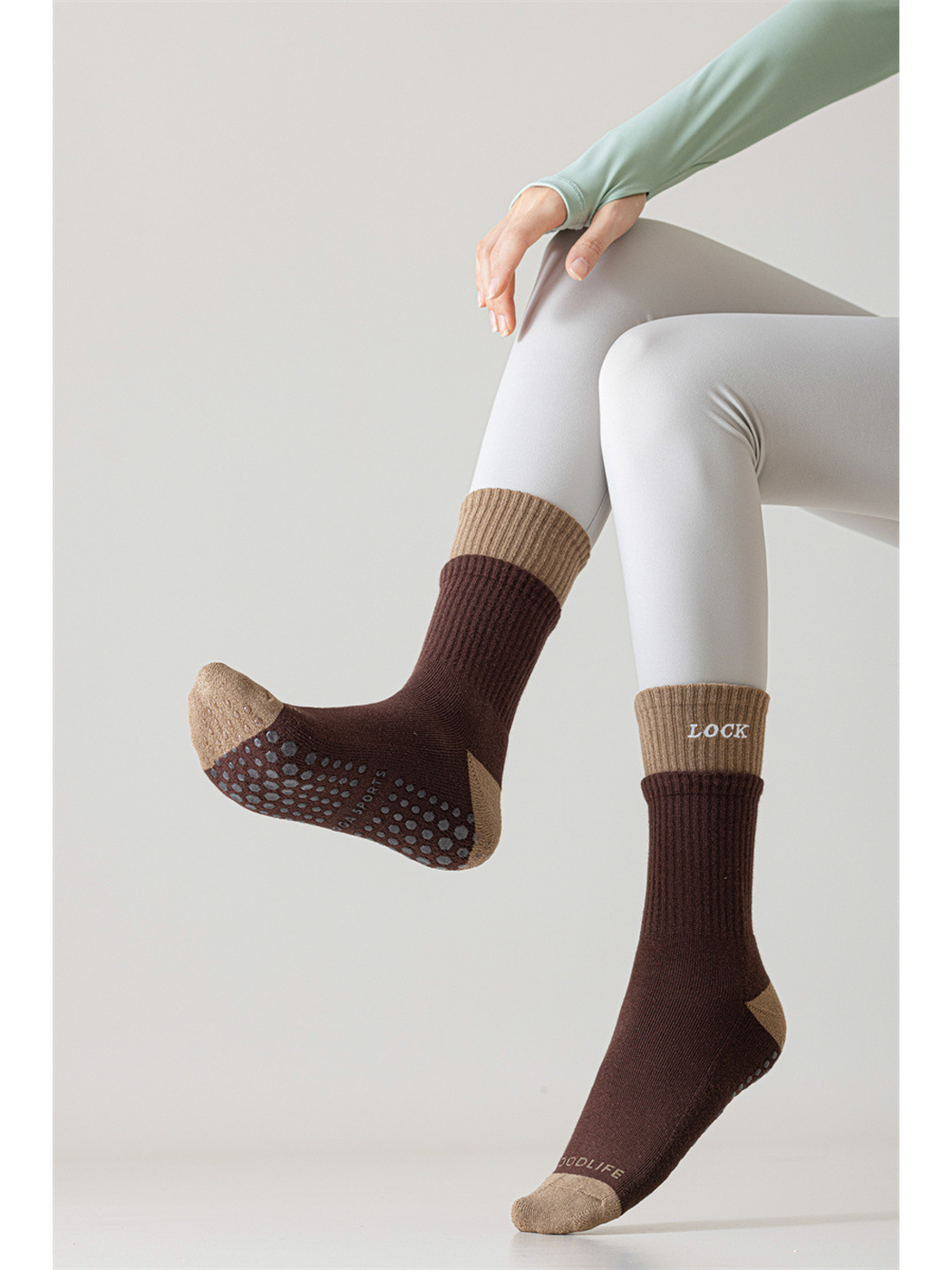 Dark brown crew socks worn with one raised sole displaying the dot pattern