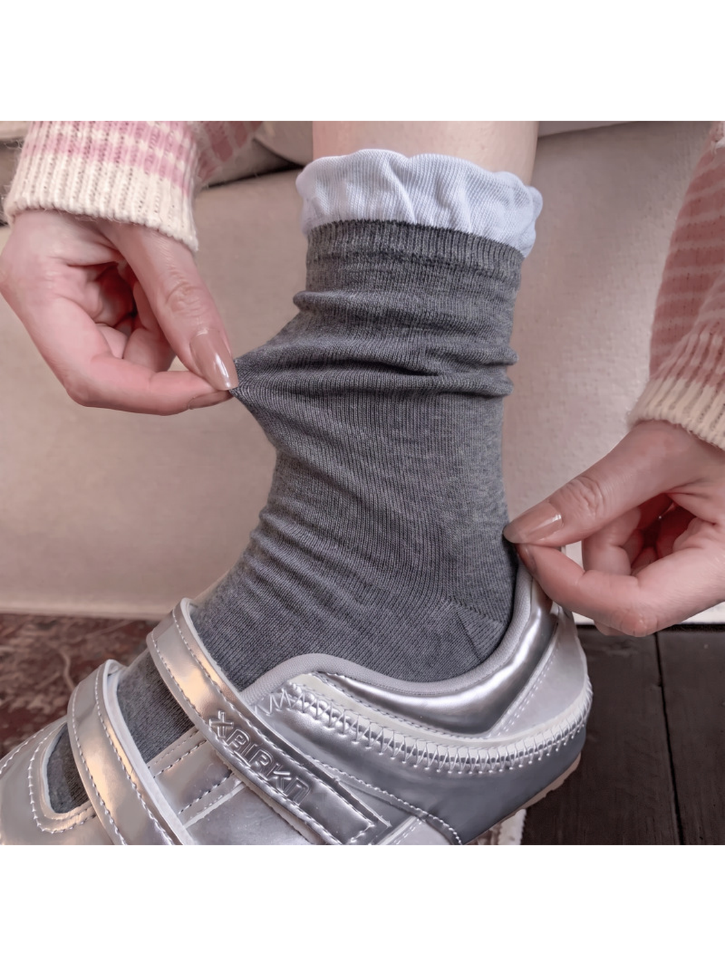 Dark gray ruffle-cuff sock stretched while worn with a silver sneaker