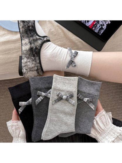 White and gray plaid-bow crew socks styled with fuzzy shoes