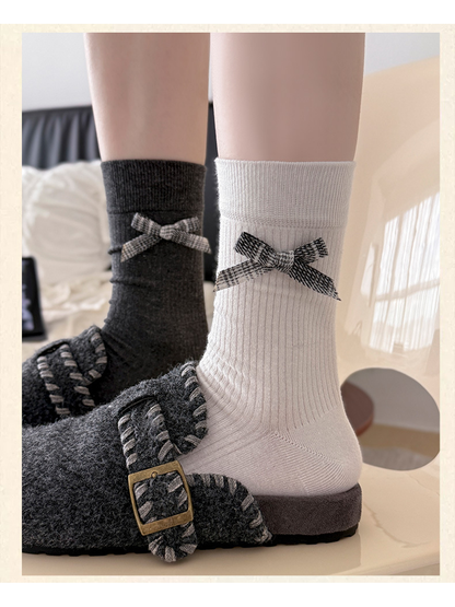 White and dark gray plaid-bow crew socks worn with fuzzy buckle shoes