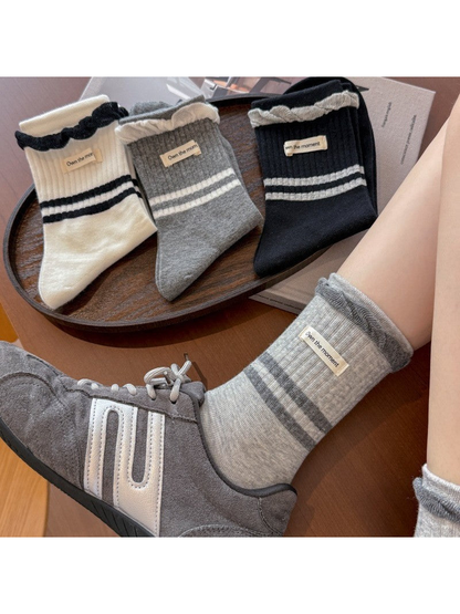 White, light gray, dark gray, and black striped crew socks displayed together
