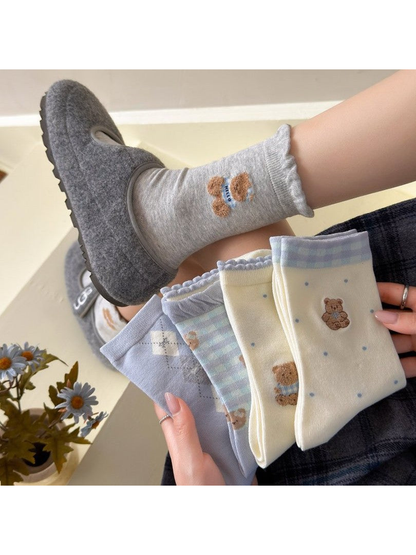 Assorted bear-pattern crew socks styled with gray slippers