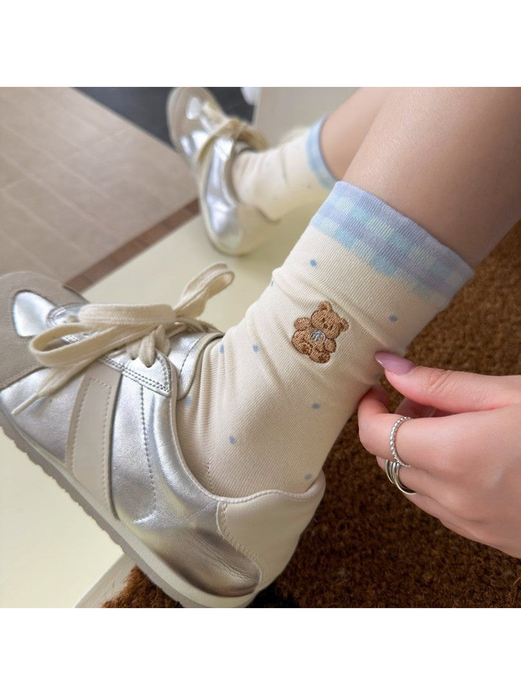 Ivory polka-dot bear crew socks worn with silver sneakers