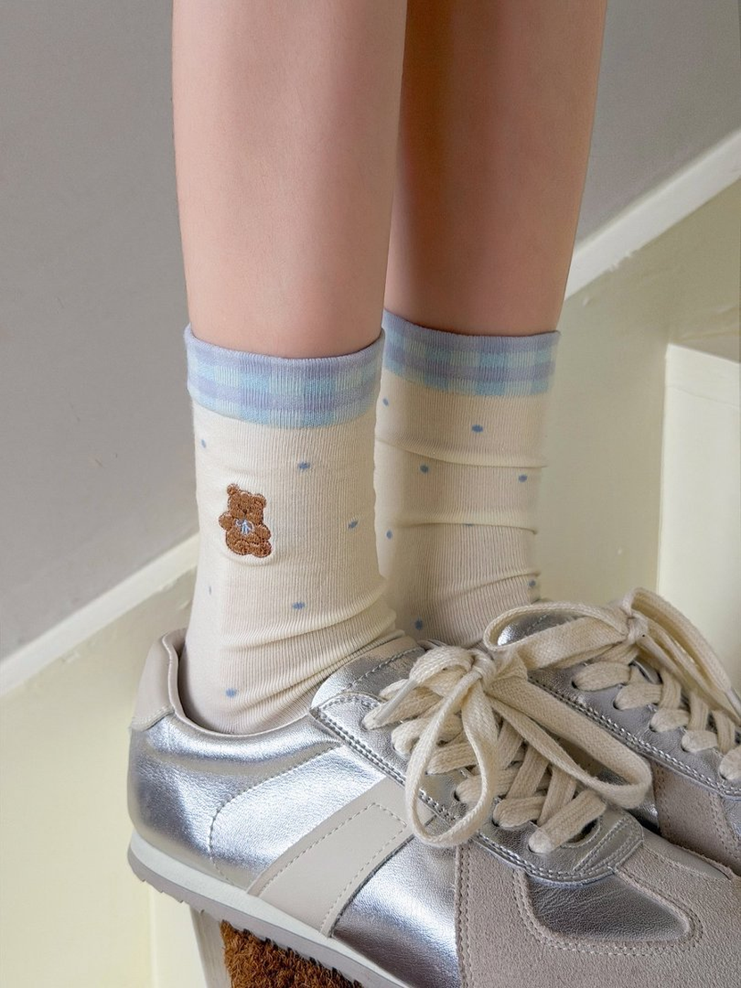 Ivory polka-dot bear crew socks worn with silver sneakers