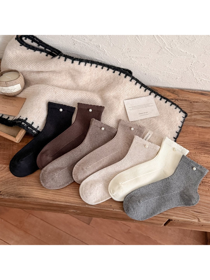 Seven colors of ribbed crew socks with pearl-like cuff beads arranged together