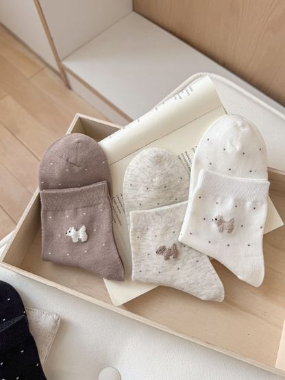 Brown, oatmeal and white dotted crew socks folded to show their dog motifs