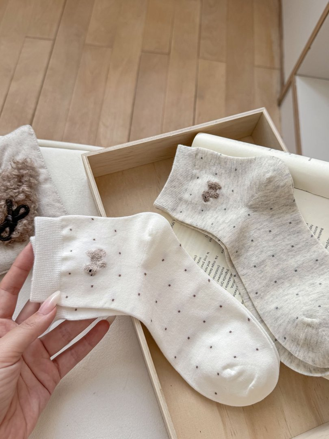 White and oatmeal dotted crew socks laid flat with raised dog motifs