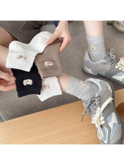 Bear-applique socks in five colors displayed with gray socks worn with sneakers