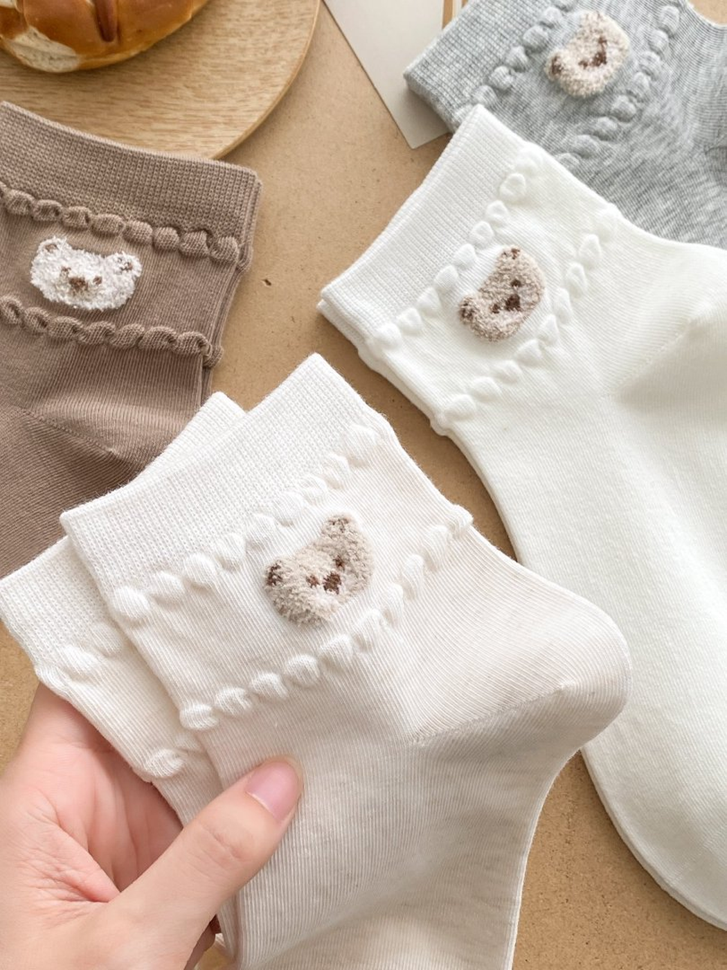 Close-up of bear-face appliques and raised trim across several sock colors