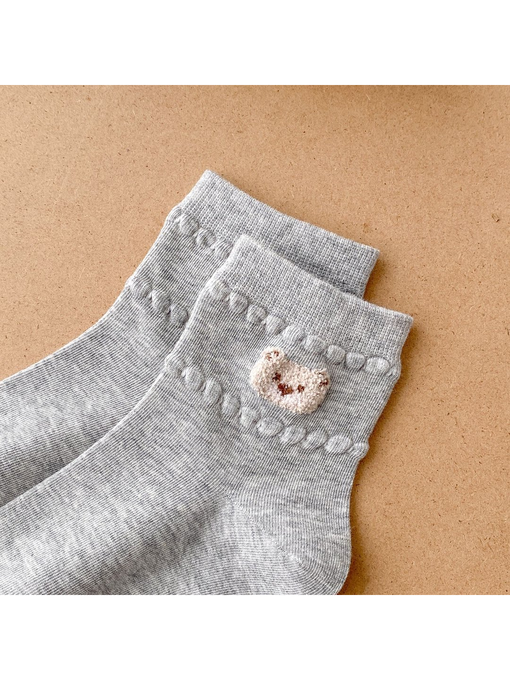 Close-up of gray sock cuffs with bear-face applique and raised bobble trim