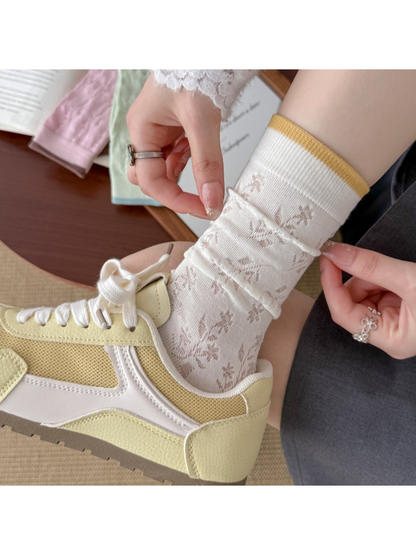 Close-up of the ivory sock's floral openwork and mustard-edged ribbed cuff