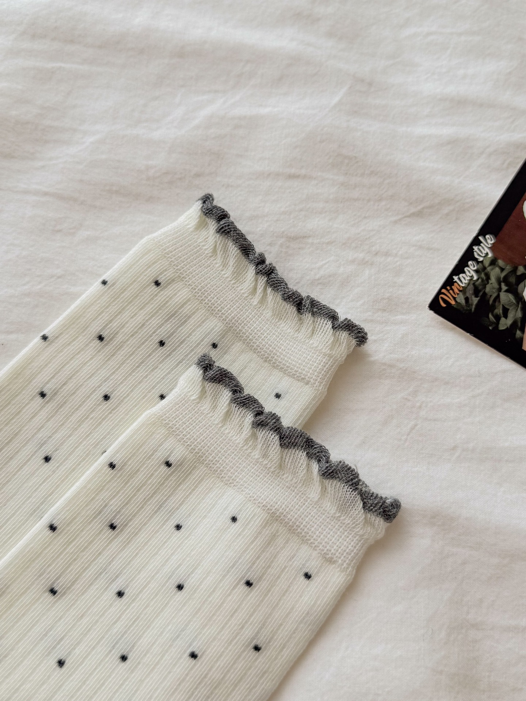Close-up of dark ruffled cuffs and fine ribbing on ivory polka-dot socks