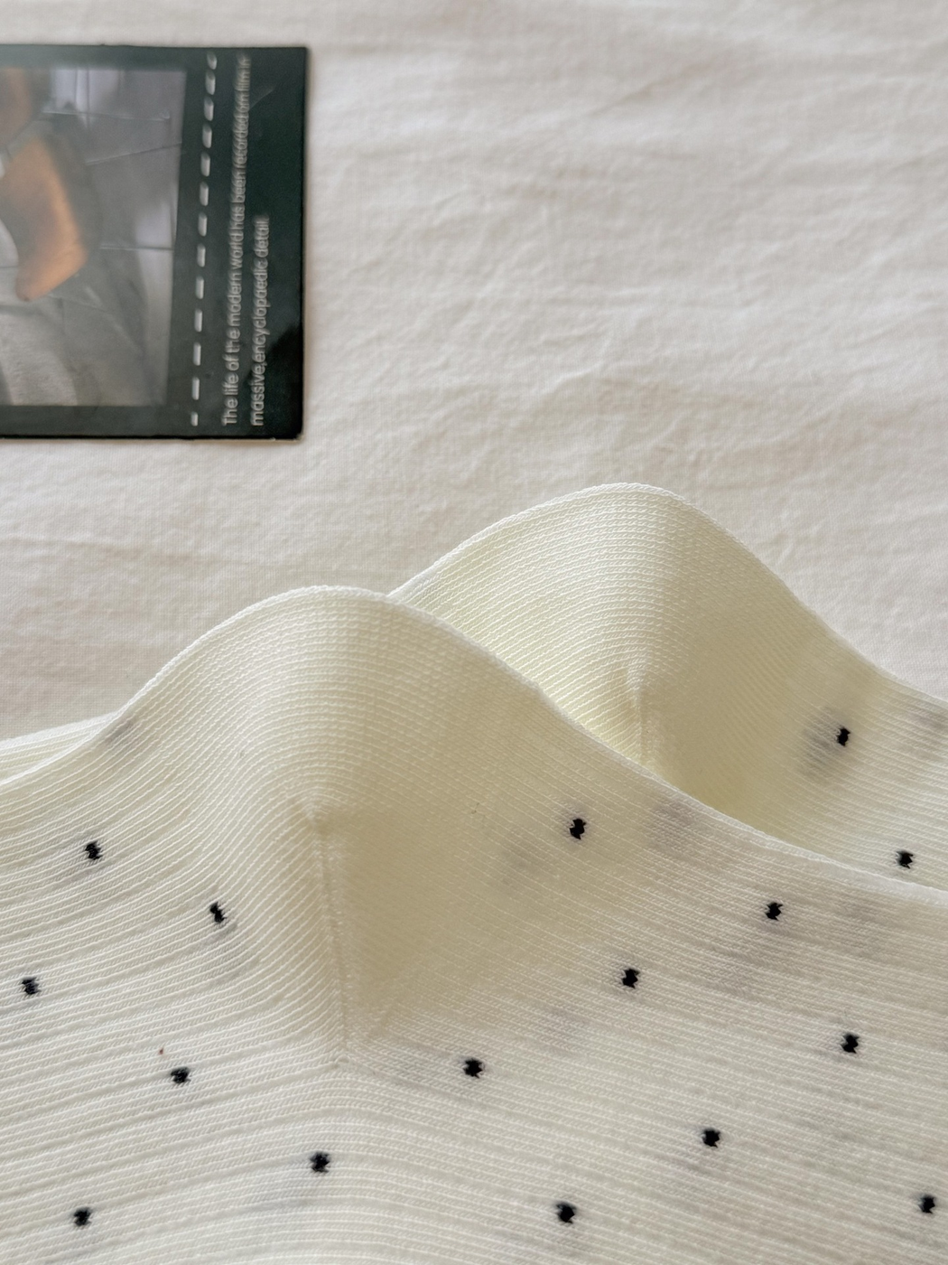 Close-up of fine ribbing and small dark dots on ivory socks