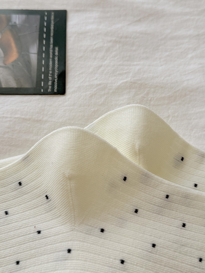 Close-up of fine ribbing and small dark dots on ivory socks