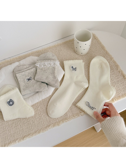 Ivory and light gray crew socks with assorted embroidered motifs and cuff details
