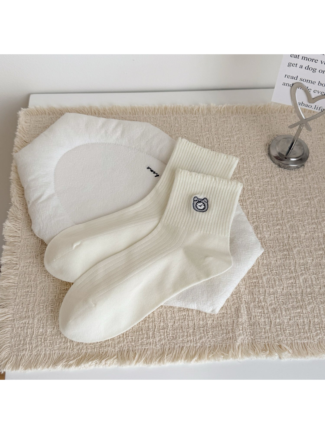 Ivory crew socks with an embroidered alarm clock motif, laid flat