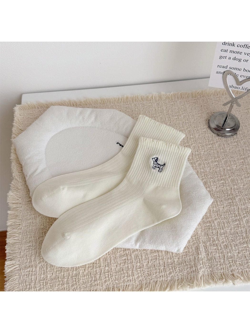 Ivory crew socks with an embroidered dog motif, laid flat