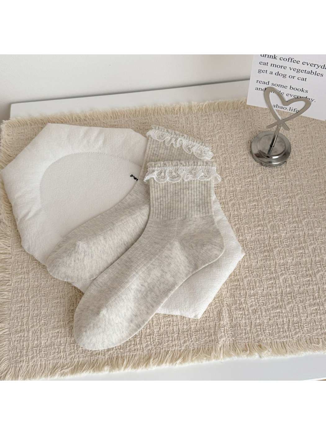 Light gray crew socks with lace-trimmed cuffs, laid flat