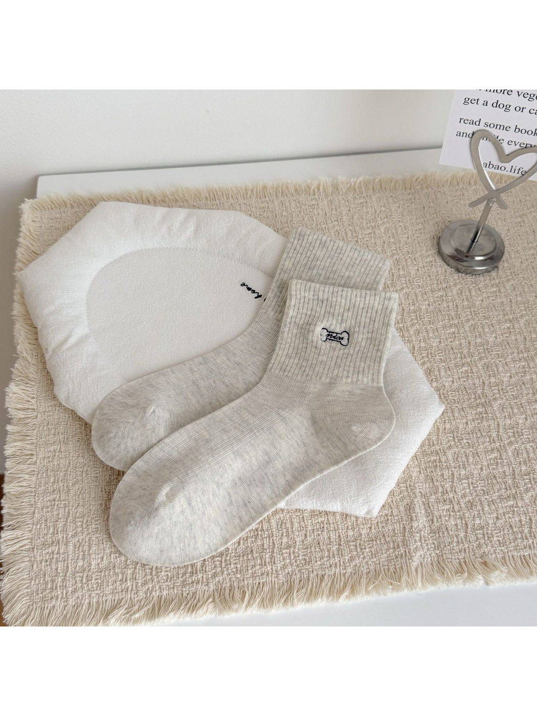 Light gray crew socks with an embroidered bone motif, laid flat