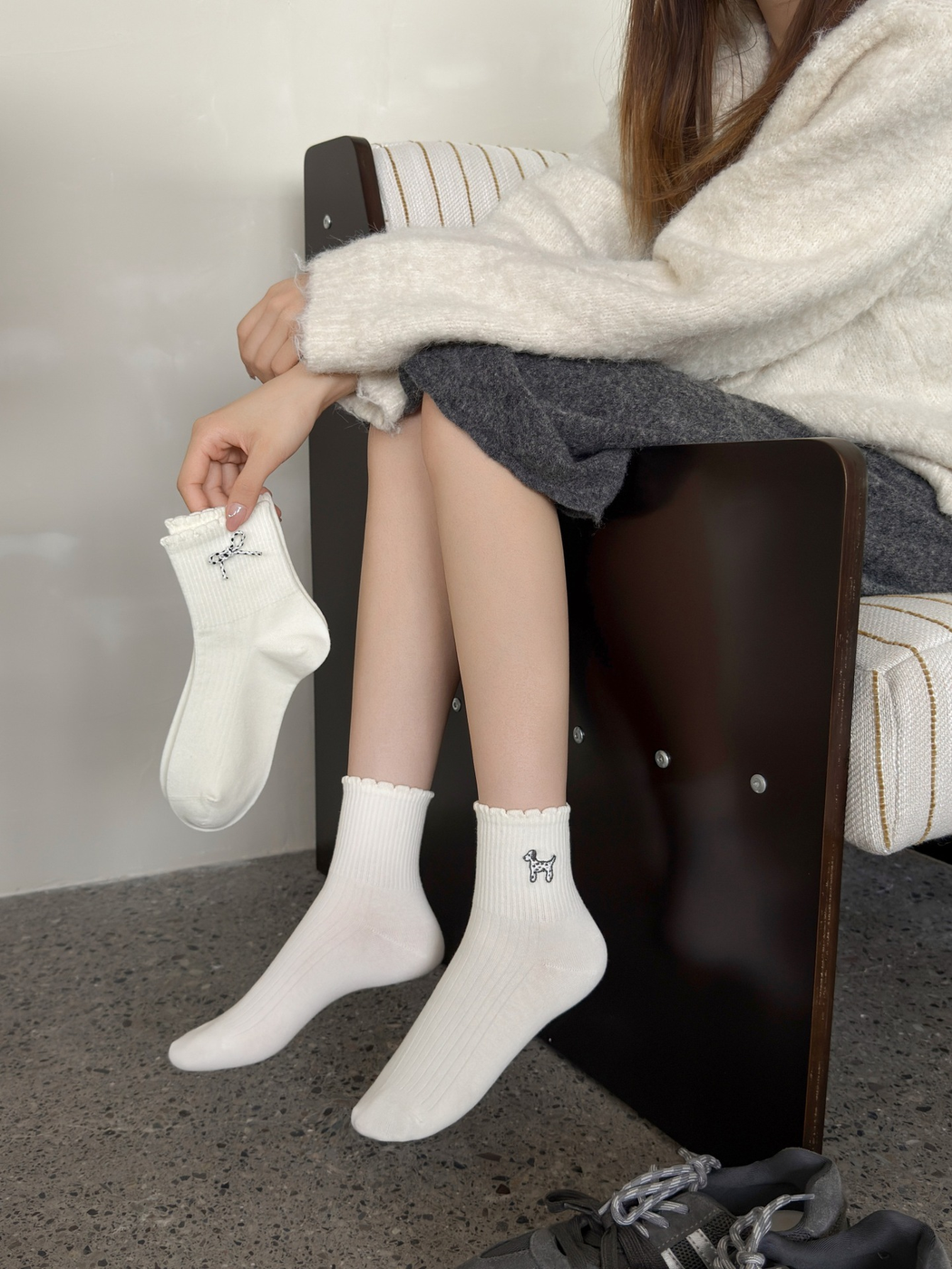 Ivory dog-motif crew socks worn while a bow-detail sock is held