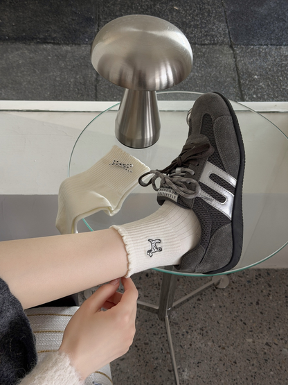 Ivory bone-motif crew socks styled with gray sneakers