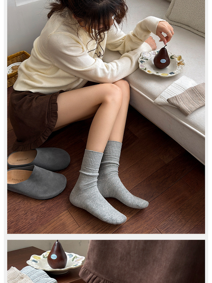 Light gray textured crew socks worn in a seated indoor setting