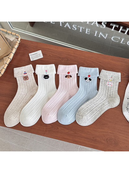 Five embroidered crew sock colors arranged side by side on a wooden table