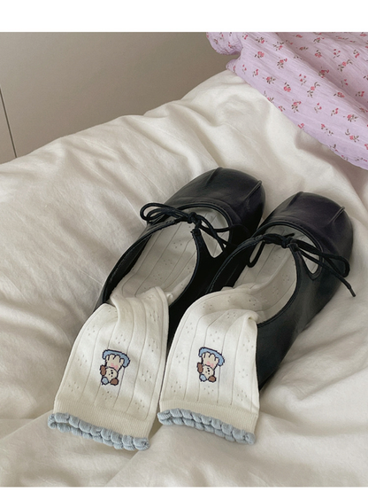 Pair of ivory dog motif crew socks styled with black lace-up flats