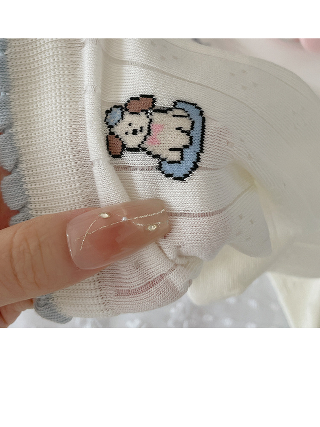 Close-up of a knit dog motif below a pale blue scalloped sock cuff