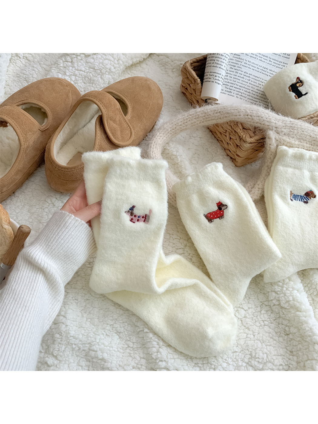 Ivory fuzzy socks with assorted embroidered dog motifs in a styled display
