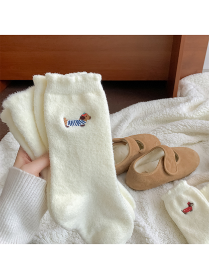 Close view of ivory fuzzy socks with blue-striped dog embroidery