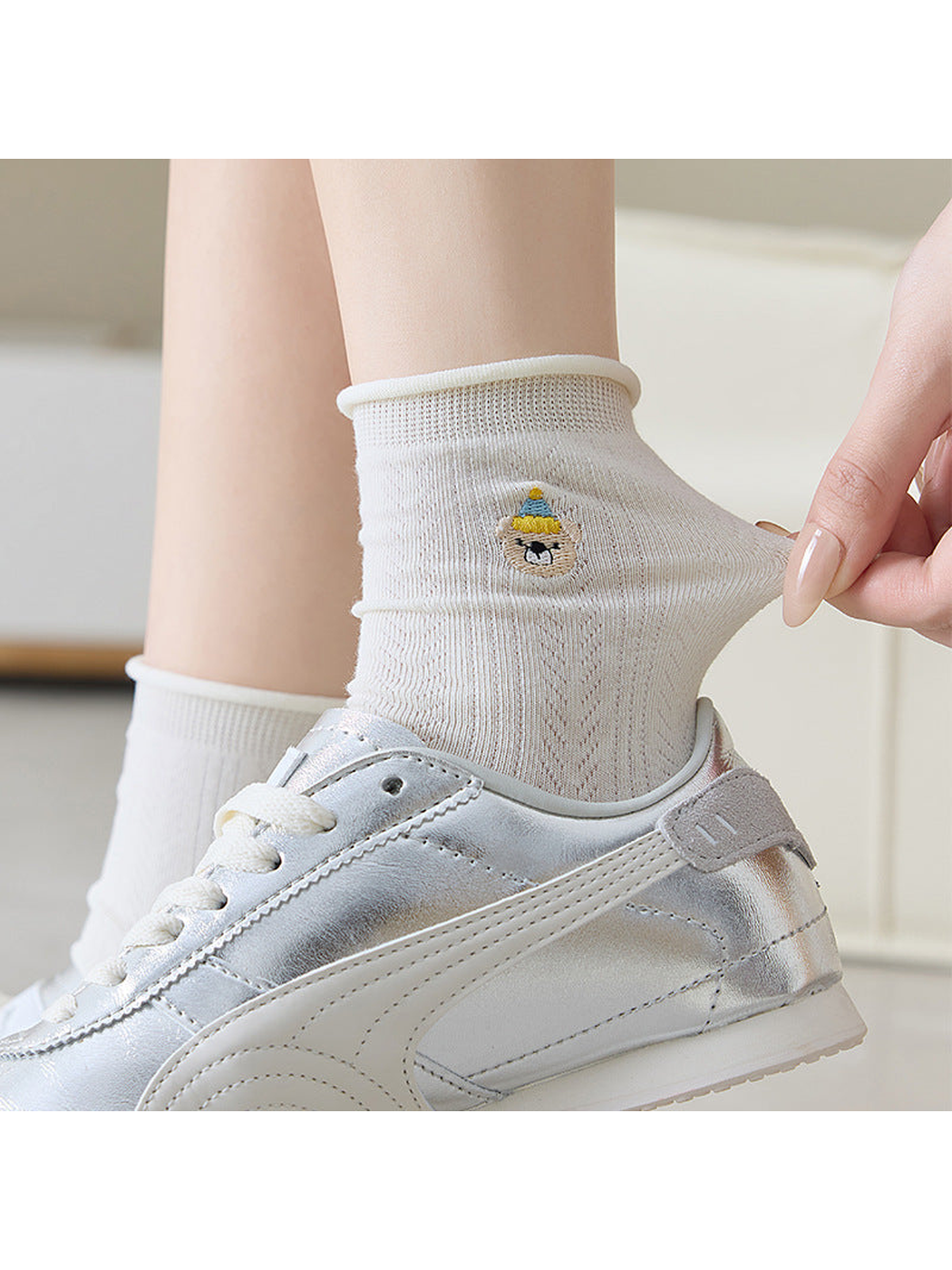 Ivory pointelle crew sock worn with a silver sneaker and gently stretched at the ankle