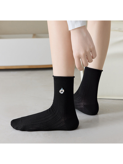 Black pointelle crew socks with a small embroidered dog motif, worn view