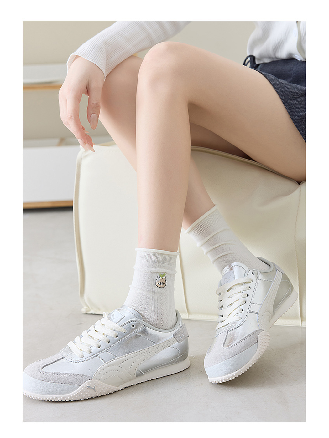 Ivory pointelle crew socks with an embroidered cat motif, styled with silver sneakers
