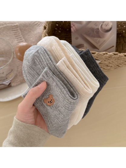 Close-up of folded bear-motif socks in gray, cream, white and dark gray