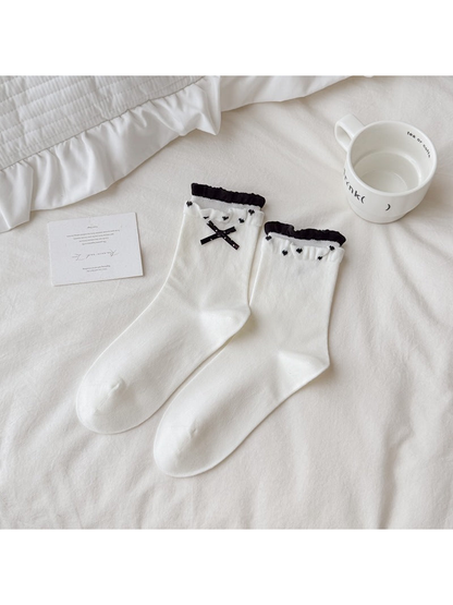 White crew socks with black bows, heart motifs and ruffled cuffs