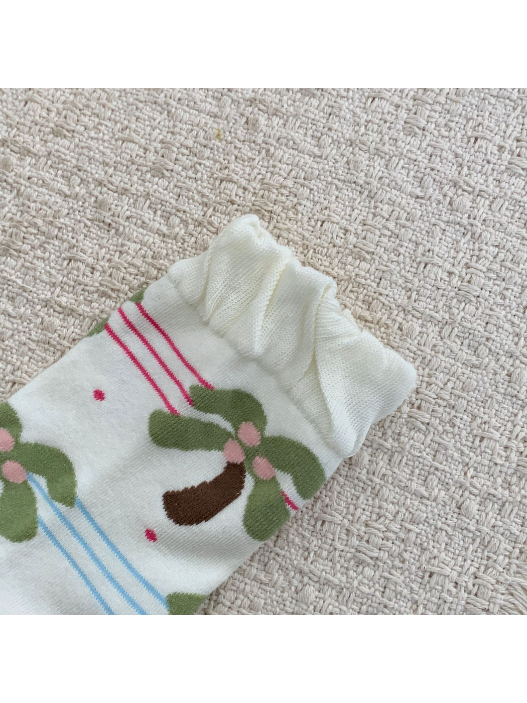 Close-up of the wavy ruffled cuff on an ivory palm tree sock
