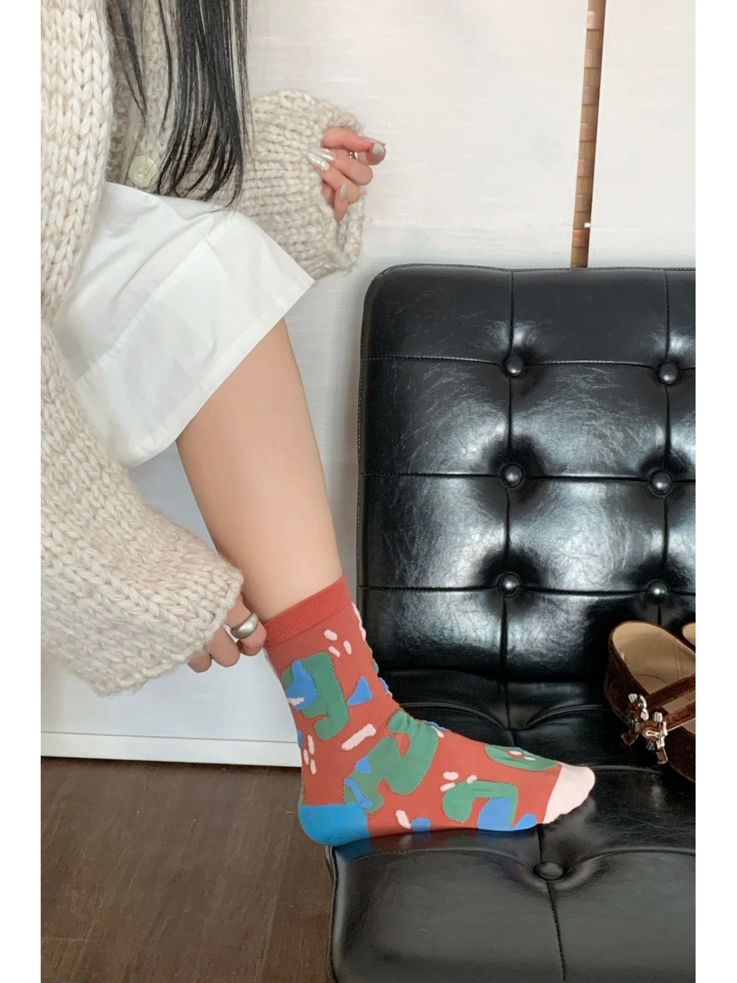 Brick-red crew sock shown from the side with raised abstract motifs