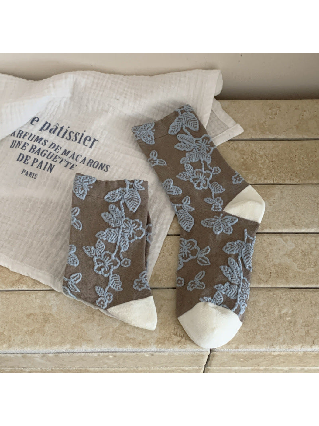 Greige floral and butterfly crew socks with light blue motifs and white toe and heel panels