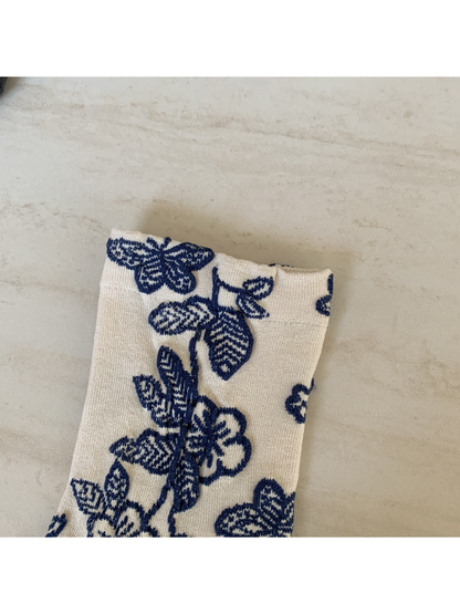 Close-up of raised navy butterfly and floral motifs on the cream sock
