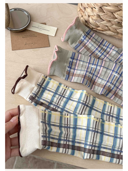 Close-up of ivory and gray plaid sock patterns and rolled cuffs