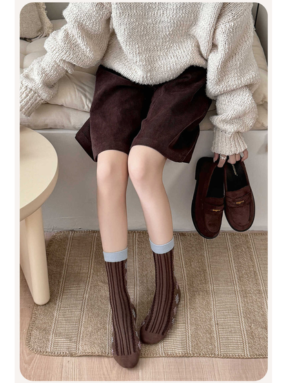 Coffee brown argyle crew socks worn with a neutral sweater and shorts